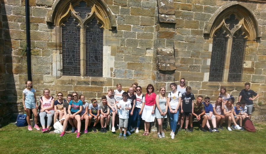 SchÃ¼lergruppe mit ihrer Lehrerin in England bei Sonnenschein vor eine Kirche stehend