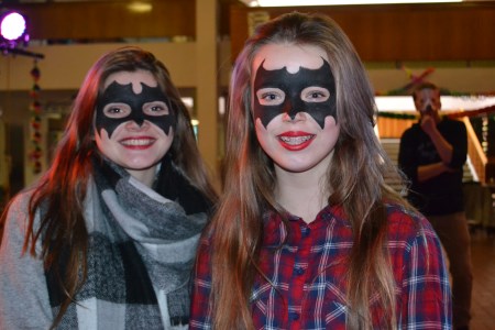 Zwei SchÃ¼lerinnen mit knallroten Lippen und einer Fledermausmaske im Gesicht.