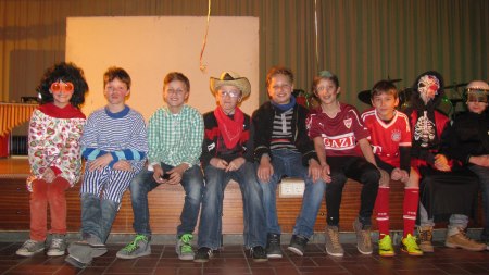 verkleidete Schülergruppe sitzt auf der Bühne im Musiksaal beim SMV Fasching