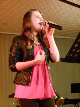 RSÖ on Stage: Schülerin singt ein Lied und hat ein Mikrofon in der linken Hand.
