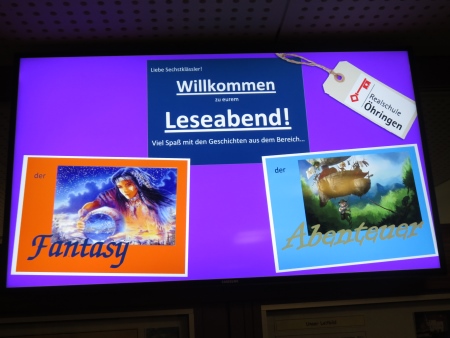 Leseabend in der Realschule Öhringen. Ankündigung auf einem Bildschirm: Liebe Sechstklässler! Willkommen zu eurem Leseabend! Viel Spaß mit den Geschichten aus dem Bereich der Fantasy und der Abenteuer.