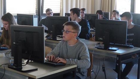 Schülerinnen und Schüler sitzen vor Bildschirmen in einem Computerraum