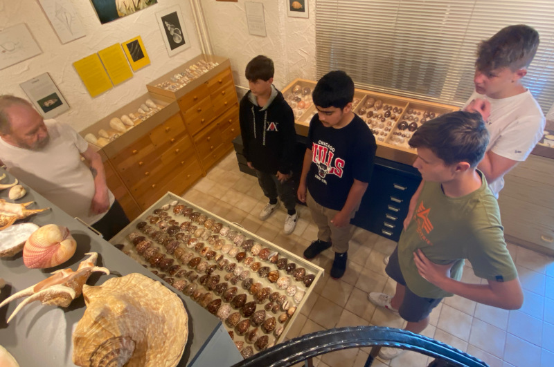 SchÃ¼ler im Meeresmuseum in Cappel. Kurt Kreipl steht neben den SchÃ¼lern, in eine geÃ¶ffneten Schublade sieht man zahlreiche Muscheln.
