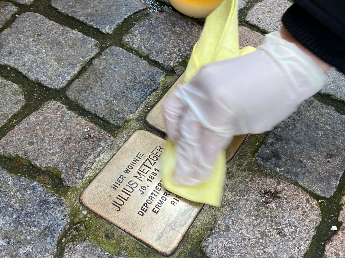 Der Stolperstein vor dem ehemaligen Haus von Julius Metzger wird gereinigt.